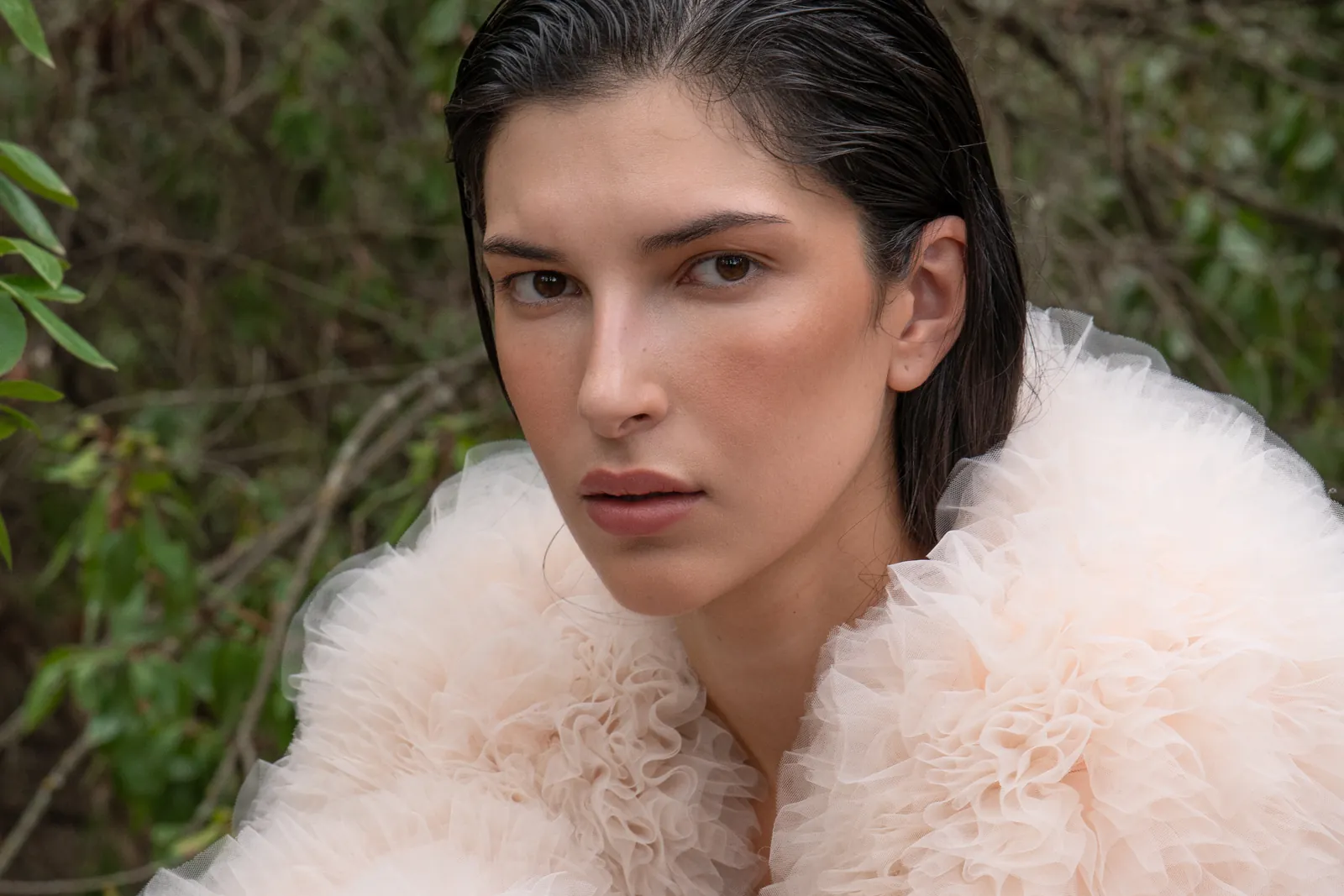 Bruma: primer plano de la modelo con el abrigo de tul rosa, el pelo mojado peinado hacia atrás